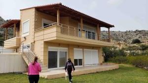two people walking in front of a house at Villa Marathi with stunning ocean view in Chania Town