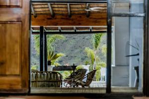 Cette chambre offre une vue sur un balcon avec des chaises. dans l'établissement Amani Lodge, à Montagu