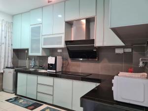 a kitchen with white cabinets and black counter tops at Westay Guest House in Melaka