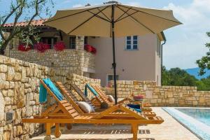 a pair of lounge chairs under an umbrella next to a pool at Villa Analucija I by Istrialux in Potpićan