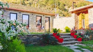 a stone house with red flower pots in the yard at Gogo Moustache Guest House in Përmet