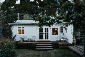 a white house with chairs in front of it at Lola Cottage in Adaminaby