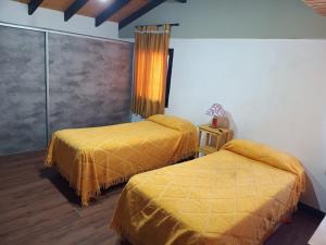 Dos camas en una habitación con sábanas amarillas. en Los soles de montaña, en Villa Pehuenia