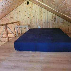 a blue bed in a room with a wooden wall at Domek dla dwojga in Pelnik