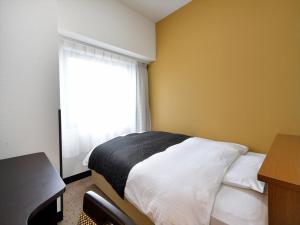 a bedroom with a bed with a window and a desk at APA Hotel Gifu Hashima Ekimae in Hashima