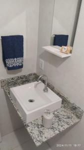 a bathroom counter with a white sink and a mirror at Orlando Braz Mini Apart in Bauru