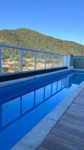 uma piscina com água azul e uma colina em Studio para locação Pereque-Açu em Ubatuba
