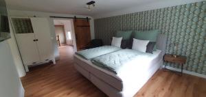 een slaapkamer met een groot bed met witte lakens bij Cottage MaarBurg in Ulmen