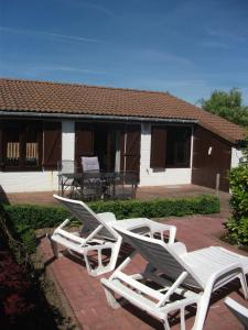 a group of white lawn chairs sitting on a patio at Ruhiges Ferienhaus im Herzen des Seebades De Haan in De Haan
