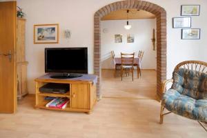 Una sala de estar con un televisor y una mesa con sillas. en Bungalow Renate, en Dornum