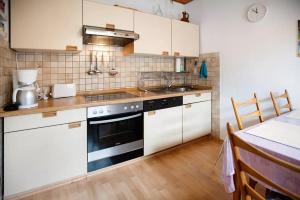 Una cocina con gabinetes blancos y un horno de estufa. en Bungalow Renate, en Dornum