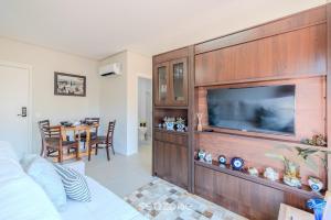a living room with a large entertainment wall with a flat screen tv at Studio Charmoso apenas 200m da Praia - PMO0404 in Florianópolis
