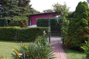 a gate to a garden with a pink house at Ferienhaus Ostseebodden in Sundhagen