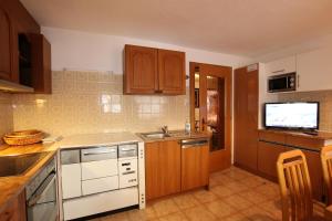 a kitchen with wooden cabinets and a tv on the wall at Ferienwohnung im Zentrum von Kappl Paznauntal PAZN100 by FeWo-PLAN in Kappl