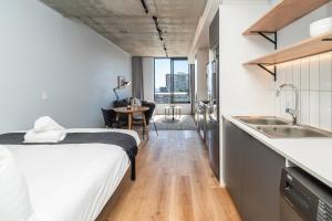 een slaapkamer met een bed en een keuken met een wastafel bij Cosy Oasis in the heart of Sea Point in Kaapstad +24 foto's