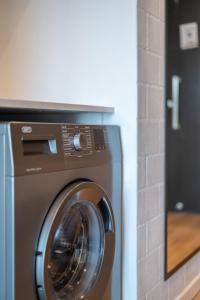 een wasmachine in een kamer met een bakstenen muur bij Cosy Oasis in the heart of Sea Point in Kaapstad