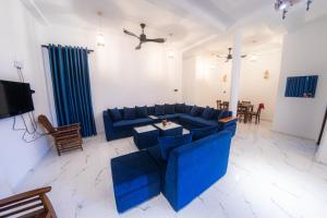 a living room with a blue couch and a tv at Bluesafiya lodge in Matara