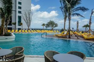 a swimming pool with chairs and tables and a building at New unit 28th Floor with Unbeatable Bayside Views in Miami