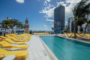 a swimming pool with yellow lounge chairs and a building at New unit 28th Floor with Unbeatable Bayside Views in Miami