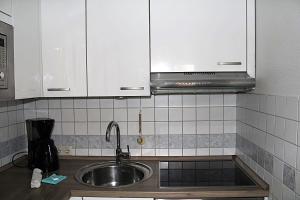 a kitchen with a sink and white cabinets at Hanseat II App112 Ostseeglanz in Grömnitzerhagen +12 photos