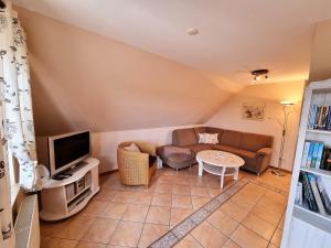 Una sala de estar con un sofá y un televisor. en Landtraum, en Oevenum