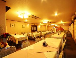 a dining room with white tables and chairs at Hakuba Tsugaike Sunrise Tanne in Otari