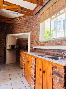 a kitchen with a sink and a brick wall at Birch stay in Kempton Park