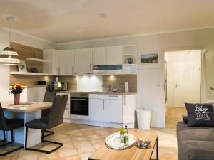 a kitchen and living room with white cabinets and a table at Fischerhuus Whg 3 in Wyk auf Föhr