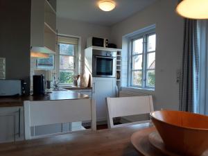 una cocina con electrodomésticos blancos, mesa y sillas en Haus Schmalstieg 7 Whg1, en Alkersum