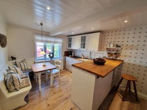 a kitchen with white cabinets and a table and a couch at Hüs Lorenzen in Oevenum