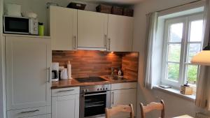 a kitchen with white cabinets and a sink and a window at Heimathafen in Wyk auf Föhr