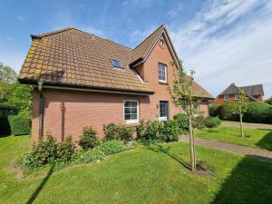 a brick house with a tree in the yard at Fluken Hüüs - Matzes Koje in Oldsum