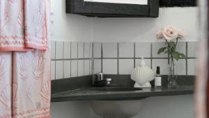 a bathroom sink with a vase of flowers on a counter at Pousada Kaya in São Sebastião +27 photos
