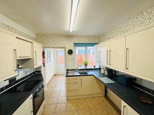 a large kitchen with white cabinets and black counter tops at The old fire station in Queensferry