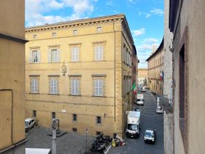 un grande edificio giallo con macchine parcheggiate di fronte di Il Nido vicino Piazza del Campo a Siena