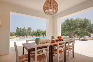 ein Esszimmer mit Tisch und Stühlen und einem großen Fenster in der Unterkunft TD Marlù Luxury Trulli Experience with Stunning Pool in Castellana Grotte