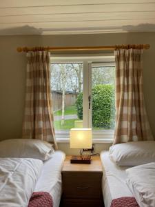 two beds in a room with a window at Churchill Lodge in Kingham