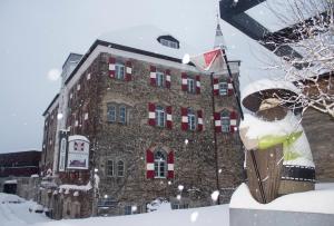 a large brick building with red windows in the snow at Hotel Sachsenklemme in Fortezza