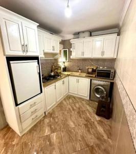 a kitchen with white cabinets and a washer and dryer at Hola bonjour corniche nador in Nador
