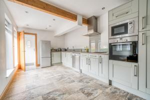 a kitchen with white cabinets and a tile floor at Luxury Cottage in New Forest Perfect for Family and Friends in Redlynch
