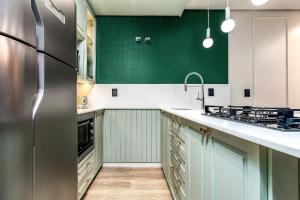 eine Küche mit grünen Wänden und einem Kühlschrank aus Edelstahl in der Unterkunft Elegância e Conforto com Piscina Aquecida by Achei in Canela