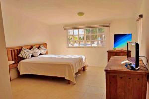 a bedroom with a bed and a flat screen tv at Studio Norte, Casa Brisamar in Puerto Morelos