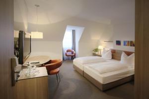 a bedroom with a bed and a desk and a tv at Hotel am Jakobsmarkt in Nuremberg