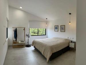 a white bedroom with a large bed and a window at Casa Tullpa in Azpitia