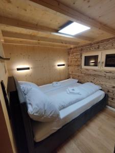 a large bed in a room with a wooden wall at ChaleMani in Pill