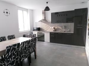 una cucina con mobili neri, tavolo e sedie di GAYANTINE - Spacieuse Confortable Proche Gayant Expo FIBRE a Roost-Warendin
