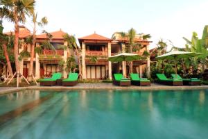 a resort with a swimming pool with green chairs and umbrellas at Ubud Tropical Garden in Ubud