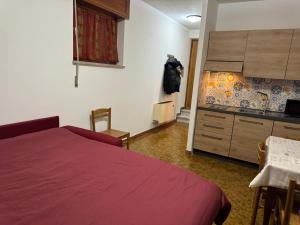 a bedroom with a red bed and a kitchen at Casa vacanze Alpine Serenity in Aosta +42 photos