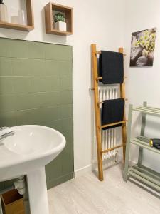 a bathroom with a sink and a shelf with towels at Le Cosy in Lannion +14 photos
