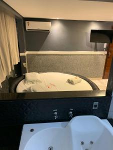 a bathroom with a bath tub and a sink at Caribe Palace Hotel Samambaia Sul in Brasilia